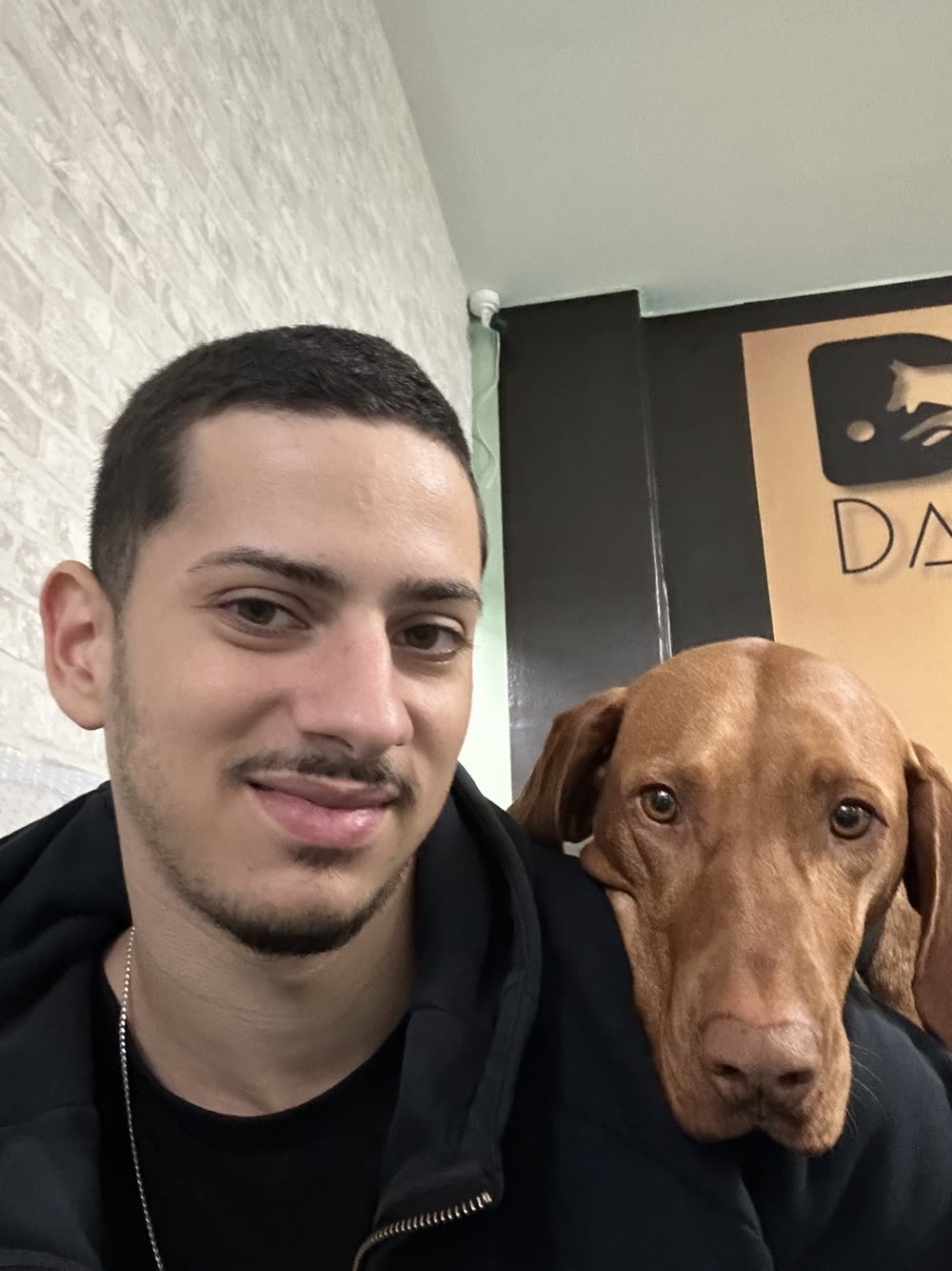 João, dog trainer at Johnny Dog Trainer, with a Vizsla resting its head on his shoulder